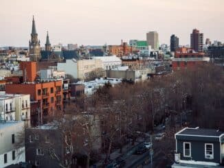 Aerial view of Brooklyn's cityscape featuring church spires and urban architecture at dusk.