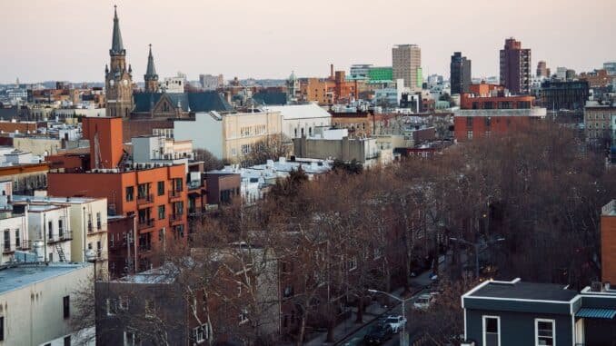 Aerial view of Brooklyn's cityscape featuring church spires and urban architecture at dusk.