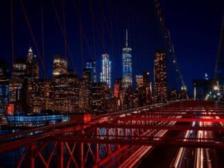 A breathtaking night view featuring the New York City skyline and iconic Brooklyn Bridge illuminated in vibrant colors.