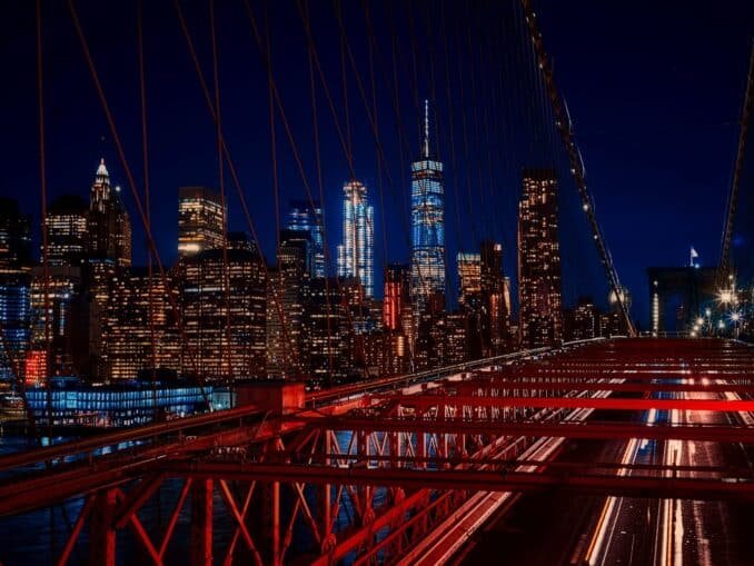 A breathtaking night view featuring the New York City skyline and iconic Brooklyn Bridge illuminated in vibrant colors.