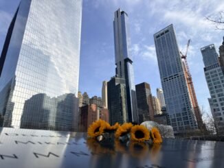 Sunflowers adorn a memorial in front of New York City's iconic skyline, showcasing poignant remembrance.