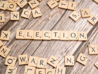 Wooden letter tiles form the word 'election' on a textured wooden surface, symbolizing voting.