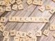 Wooden letter tiles form the word 'election' on a textured wooden surface, symbolizing voting.