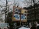 Crowd gathered with placards during a protest against Russian banks in an urban setting.