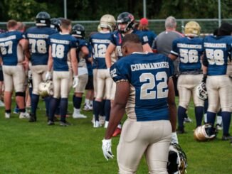 Football team players in helmets and uniforms preparing on the field.