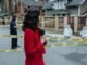 Female journalist reporting live on a crime scene investigation with police presence outdoors.