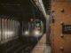 A New York City subway train approaching the platform at 6th Avenue station at night.