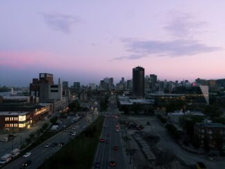 A stunning view of Montreal's skyline at sunset, featuring busy urban streets with cars and iconic buildings.