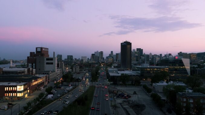 A stunning view of Montreal's skyline at sunset, featuring busy urban streets with cars and iconic buildings.