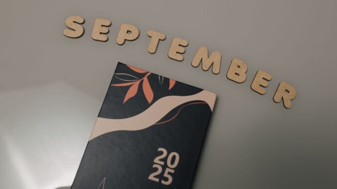 Flat lay of a 2025 calendar with September in wooden letters and an autumn design on a neutral background.