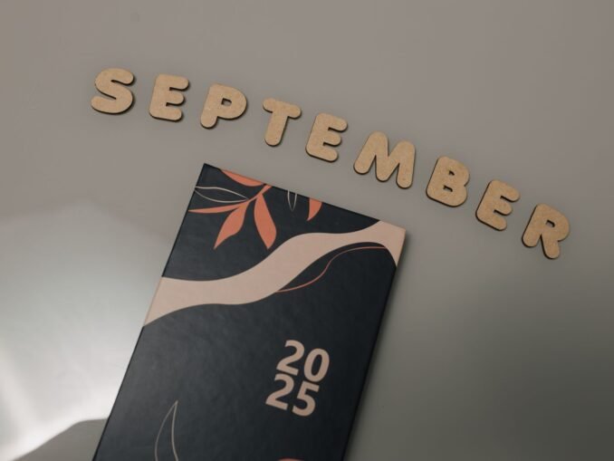 Flat lay of a 2025 calendar with September in wooden letters and an autumn design on a neutral background.